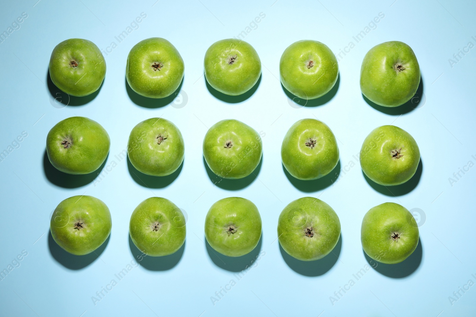 Photo of Ripe green apples on light blue background, flat lay