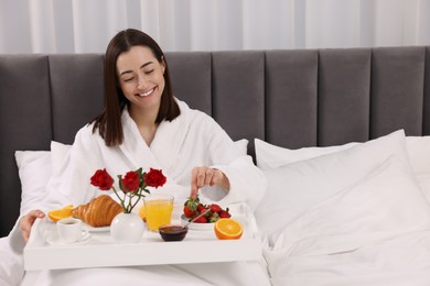 Photo of Smiling woman having breakfast in bed at home, space for text