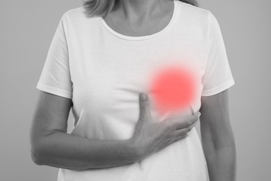 Image of Woman doing breast self-examination on grey background, closeup. Color accent effect