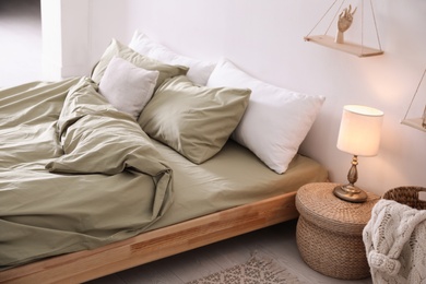 Photo of Comfortable bed with olive green linen in modern room interior