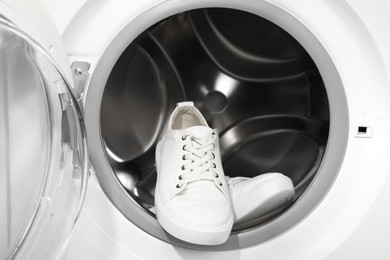 Photo of Stylish clean sneakers inside modern washing machine