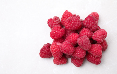 Photo of Delicious fresh ripe raspberries on white table, top view