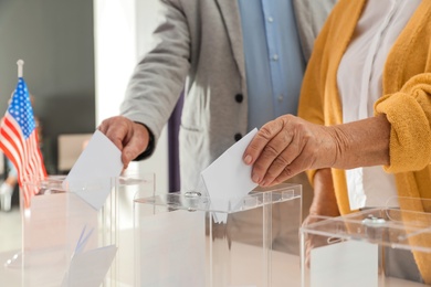 Photo of Elderly people putting ballot papers into boxes at polling station, closeup