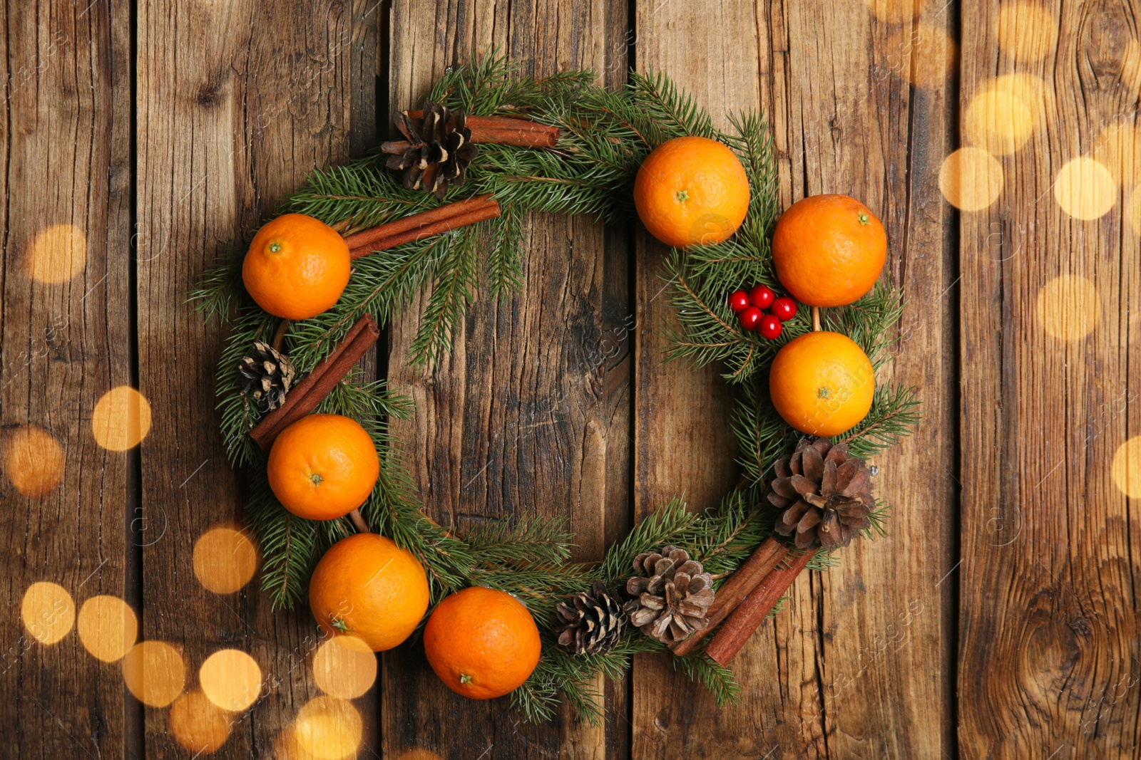 Photo of Decorative wreath with tangerines, fir tree branches and spices on wooden background, top view