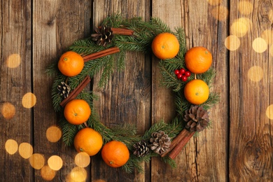 Decorative wreath with tangerines, fir tree branches and spices on wooden background, top view