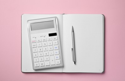 Calculator, notebook and pen on pink background, top view