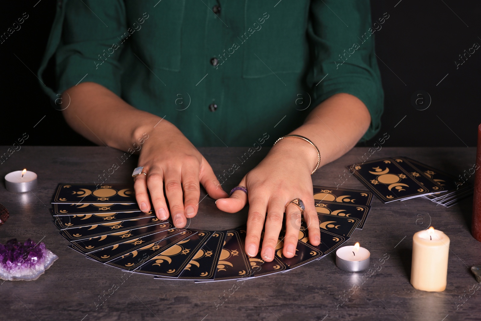 Photo of Soothsayer predicting future with tarot cards at table in darkness, closeup