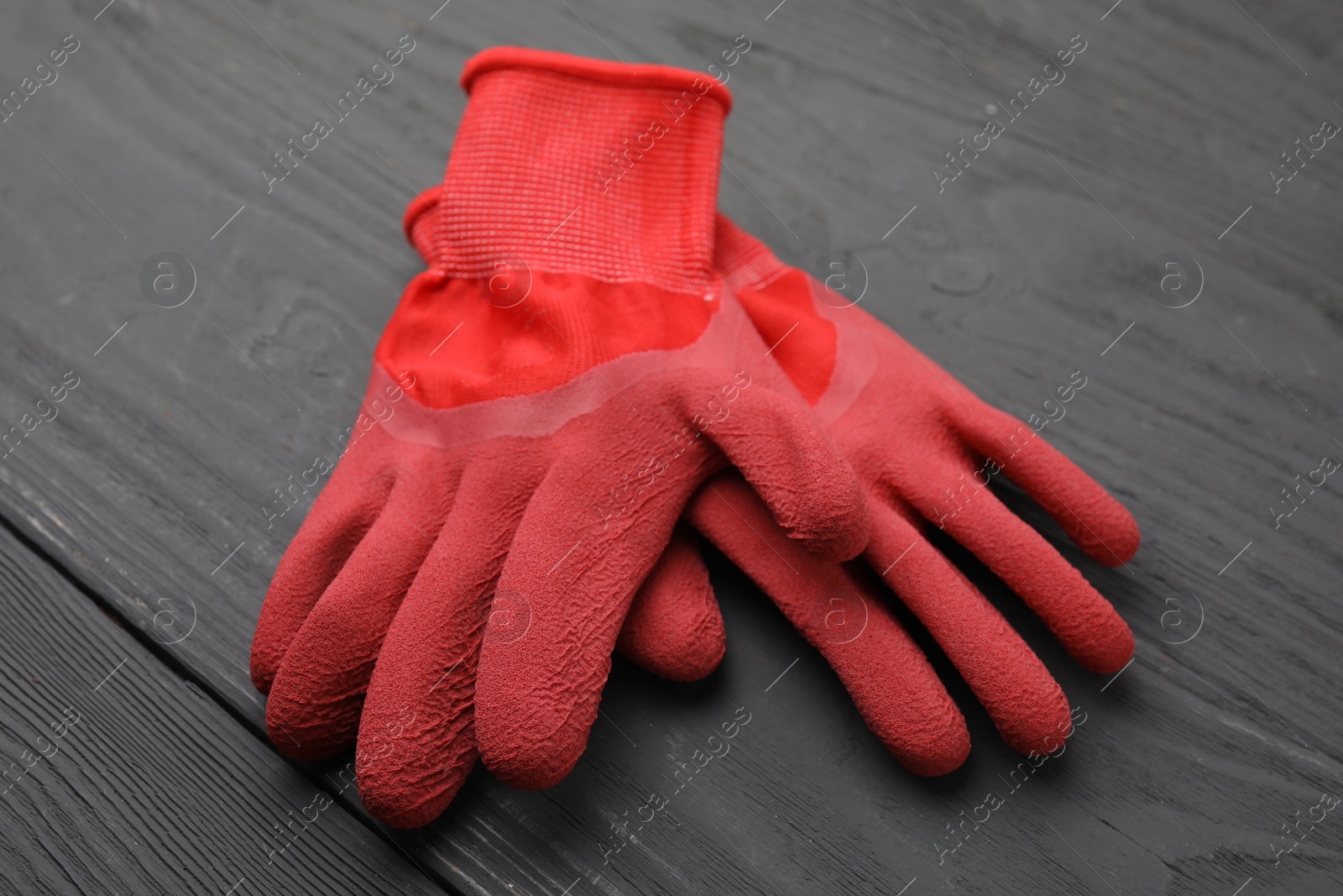 Photo of Pair of red gardening gloves on grey wooden table