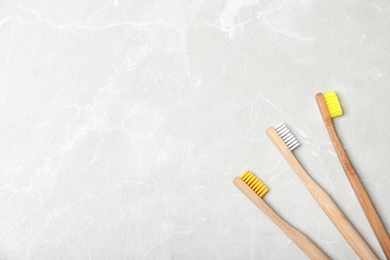 Photo of Bamboo toothbrushes and space for text on light background, top view. Dental care