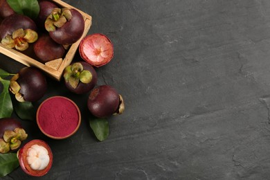 Photo of Purple mangosteen powder and fruits on black table, flat lay. Space for text