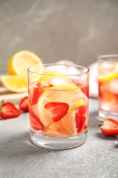 Photo of Tasty refreshing drink with strawberries and lemon on light grey table