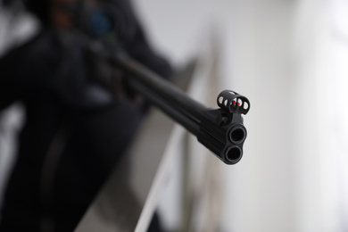 Photo of Hired professional killer indoors, focus on sniper rifle