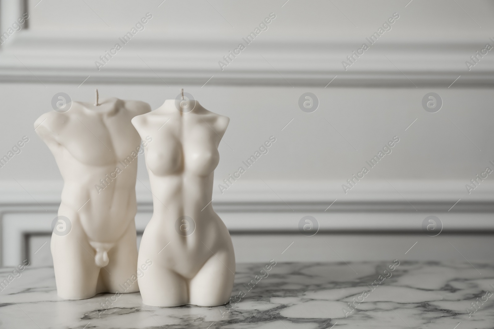 Photo of Stylish male and female body shaped candles on white marble table. Space for text