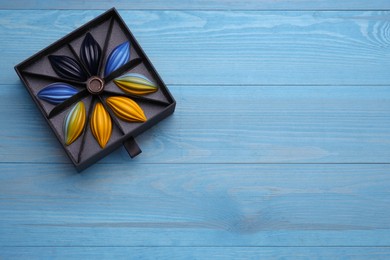 Photo of Box of tasty chocolate candies on light blue wooden table, top view. Space for text