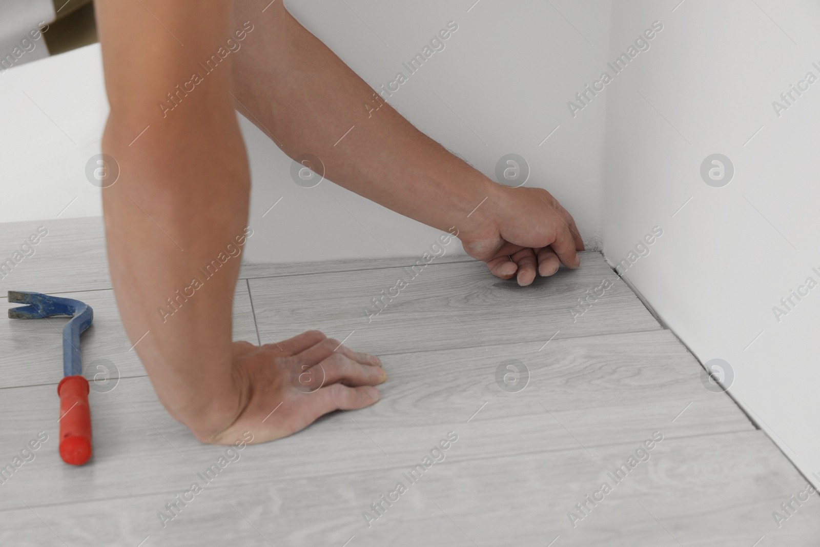 Photo of Professional worker installing new laminate flooring indoors, closeup