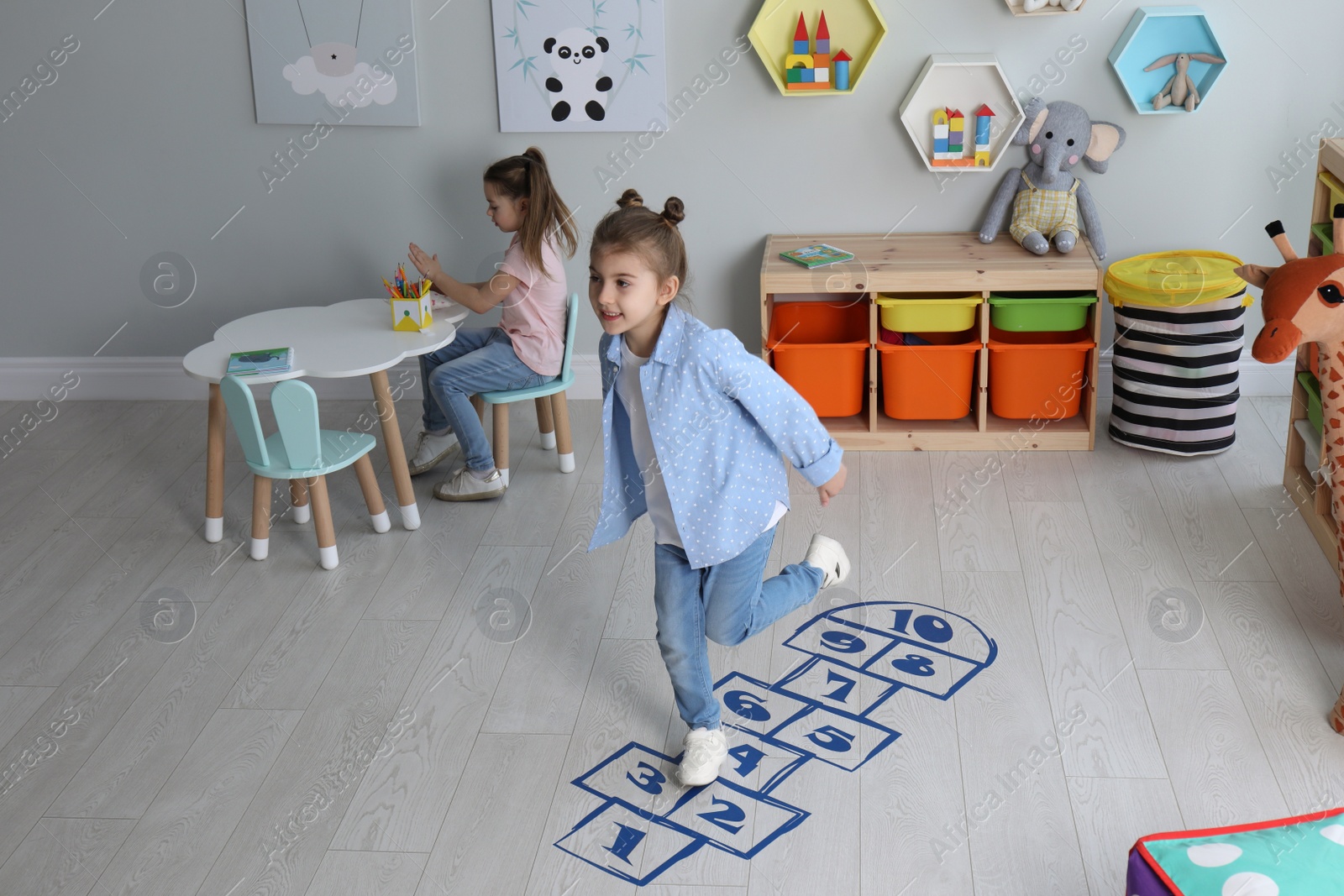 Photo of Cute little girls playing hopscotch at home