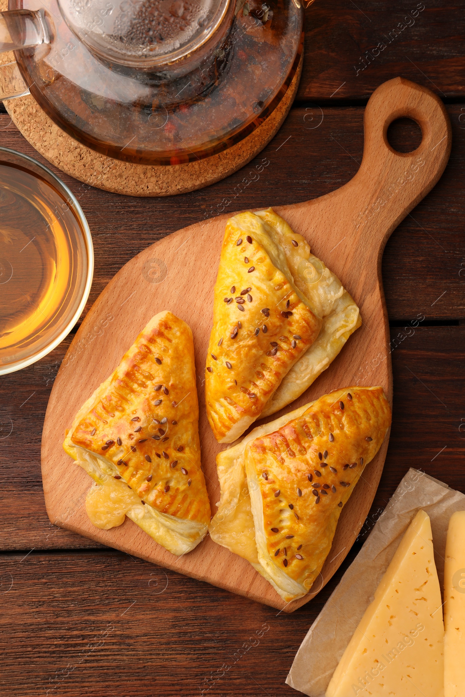 Photo of Fresh delicious puff pastry served with cheese and tea on wooden table, flat lay