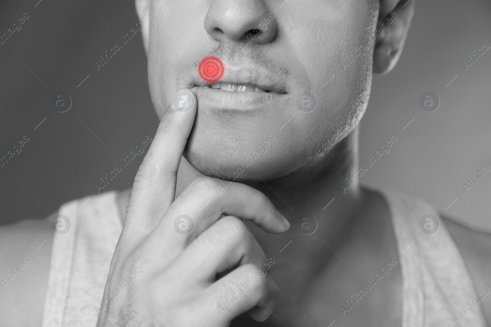 Image of Man with herpes touching lips against grey background, closeup. Black and white effect