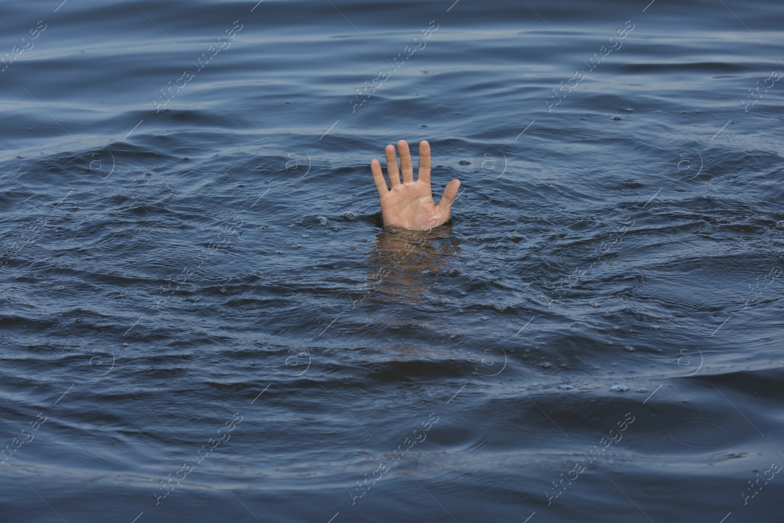 Photo of Drowning man reaching for help in sea, closeup