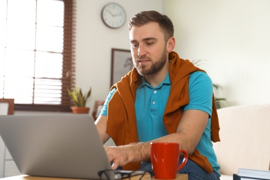 Young man using laptop at table indoors