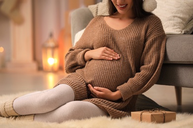 Photo of Happy pregnant woman with Christmas gift box at home, closeup. Expecting baby