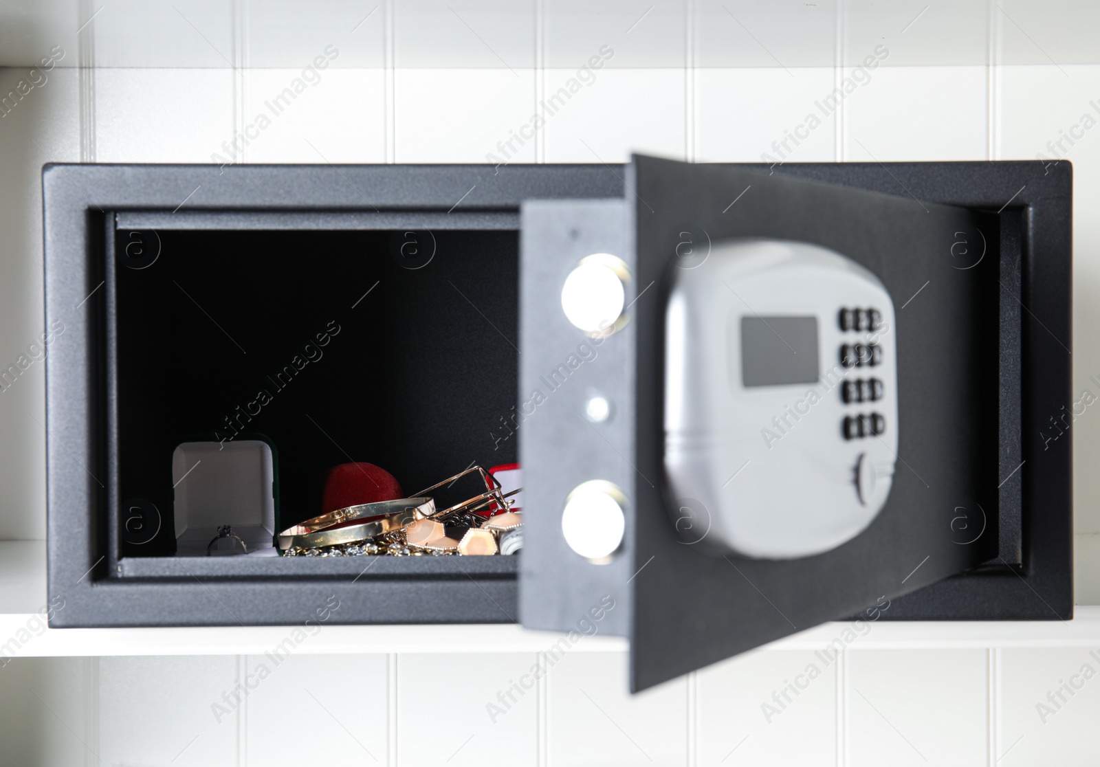 Open black steel safe with money and jewelry on shelf Photo of Open black steel safe with money and jewelry on shelf