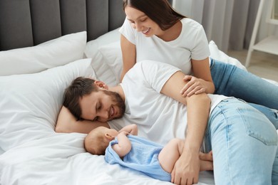 Happy family. Parents with their cute baby on bed indoors