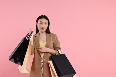 Beautiful woman with shopping bags on pink background. Space for text