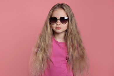 Photo of Girl wearing stylish sunglasses in shape of hearts on pink background