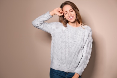 Image of Happy young woman wearing warm sweater on beige background 