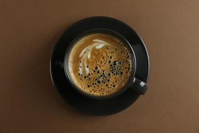 Cup of tasty coffee on brown background, top view