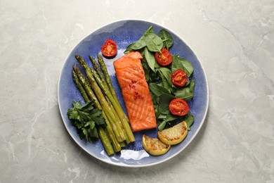 Photo of Tasty grilled salmon with tomatoes, asparagus lemon and basil on grey table, top view