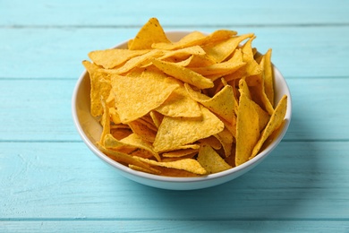 Photo of Tasty mexican nachos chips in bowl on blue wooden table