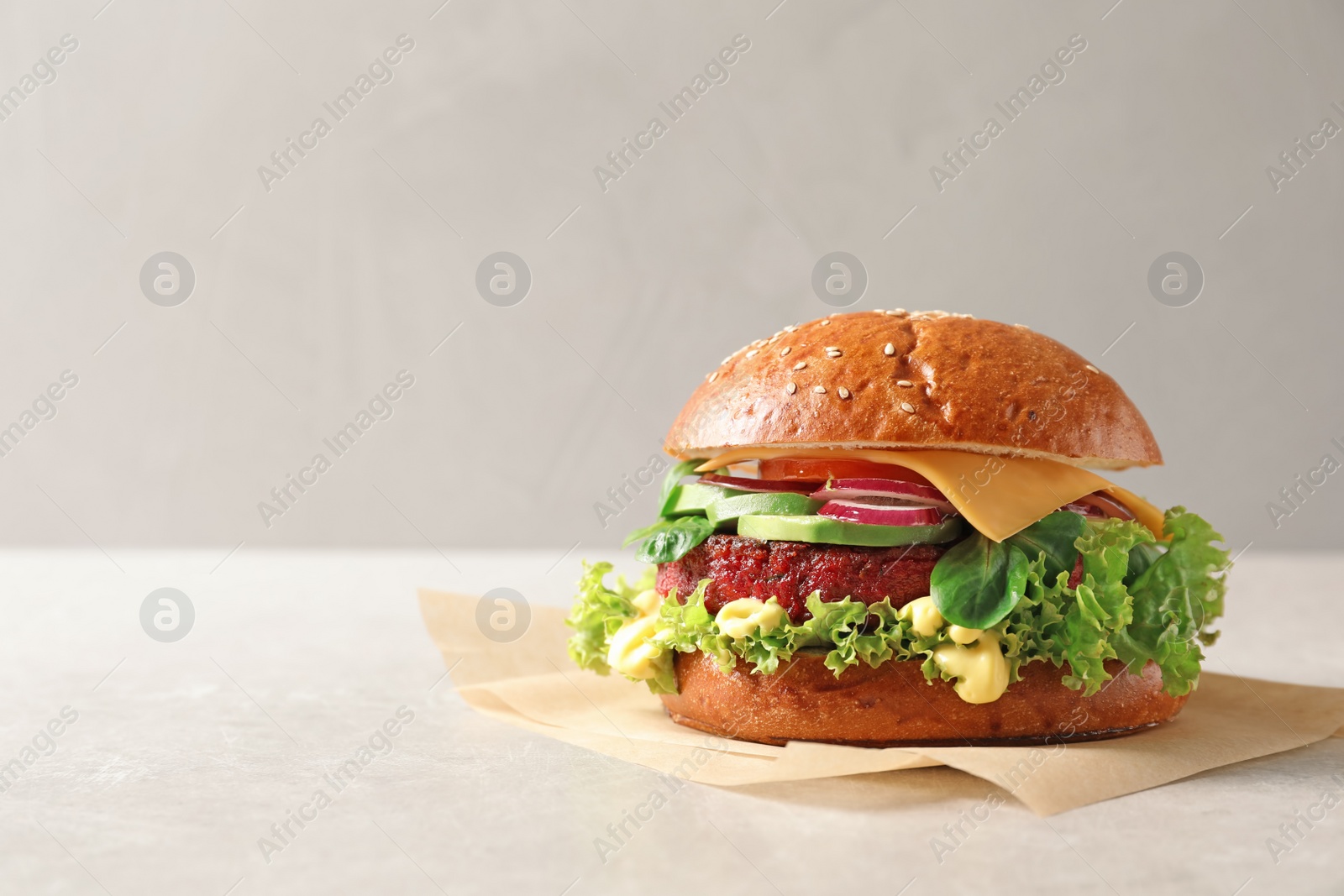 Photo of Tasty vegetarian burger with beet cutlet on table against light background. Space for text