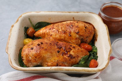 Photo of Baked chicken fillets with vegetables and marinade on grey table, closeup