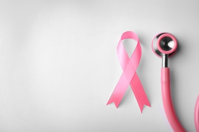 Pink ribbon and stethoscope on white background, top view with space for text. Breast cancer concept