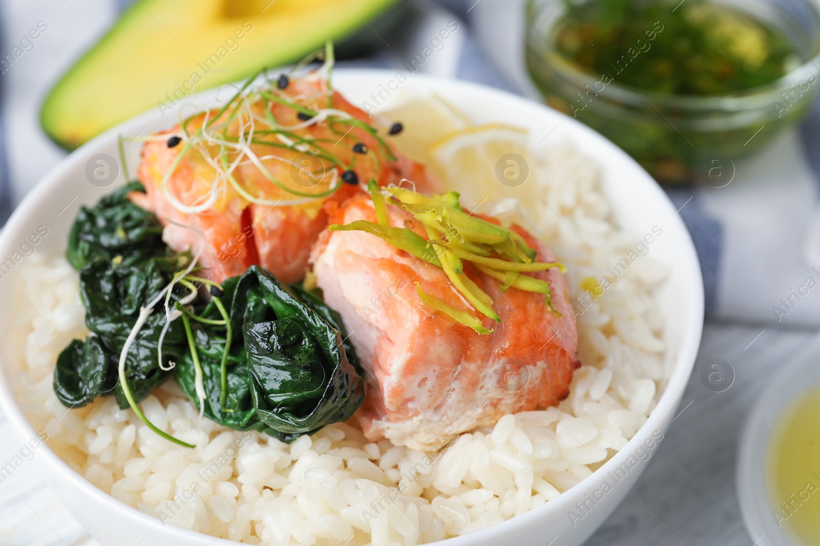 Photo of Tasty salmon with rice and spinach on white wooden table, closeup