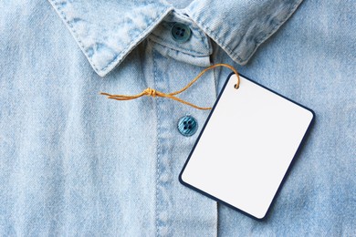 Blank tag on denim shirt, top view. Space for text