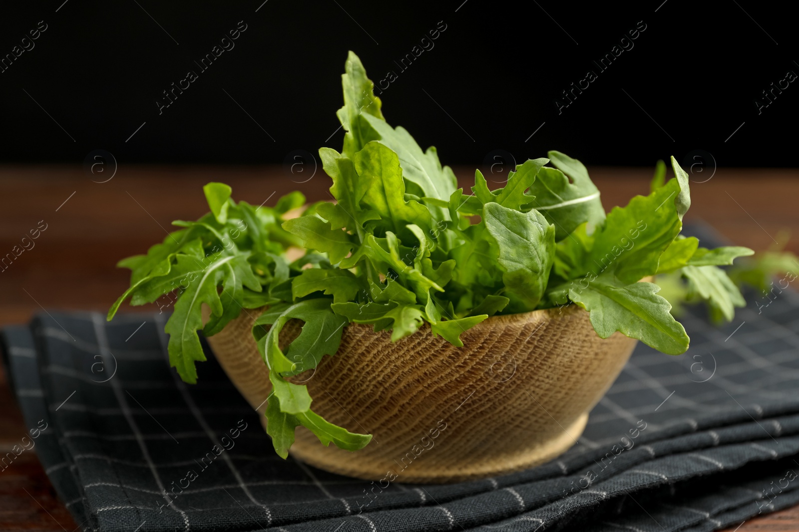 Photo of Fresh arugula in wooden bowl on table