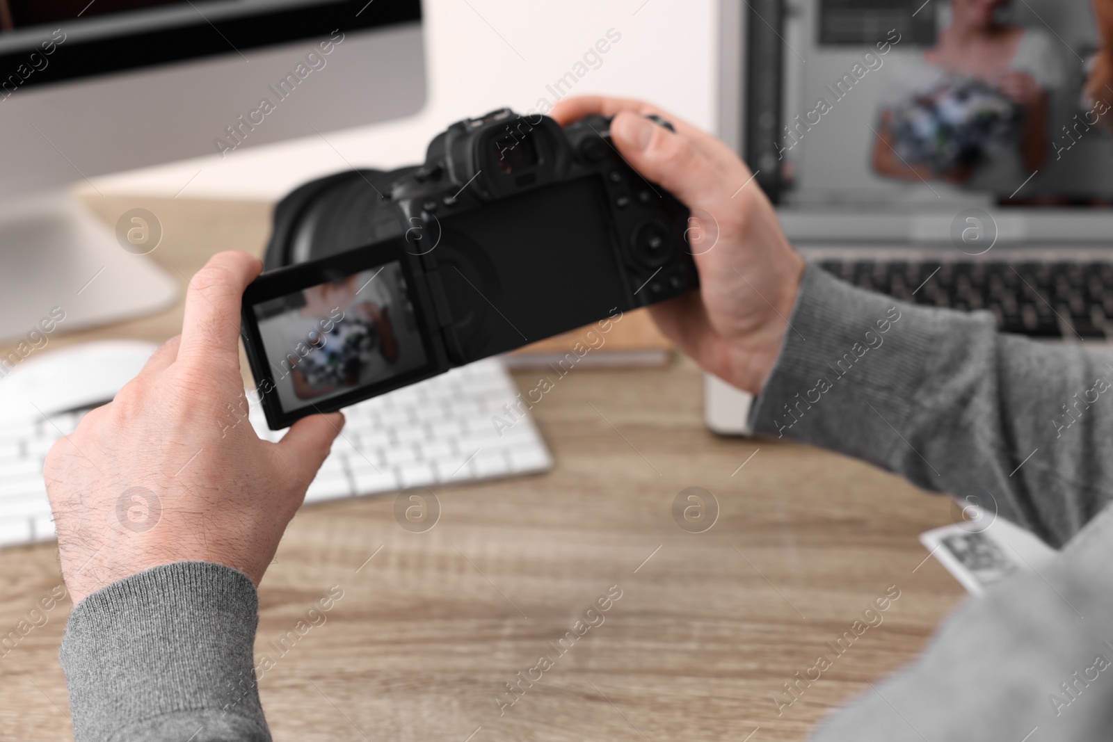 Photo of Professional photographer with digital camera at wooden table indoors, closeup