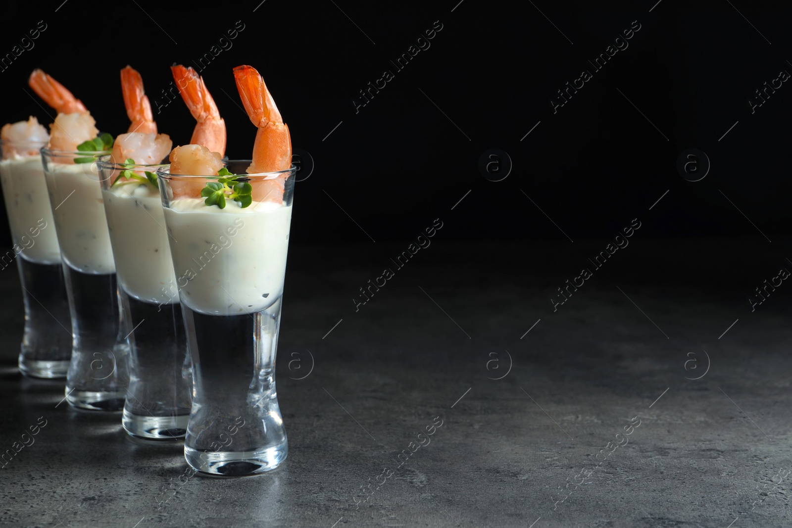 Photo of Glasses with boiled shrimps and sauce on dark background