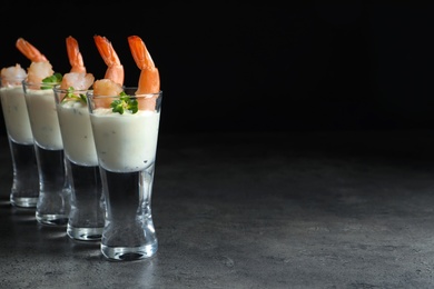 Photo of Glasses with boiled shrimps and sauce on dark background