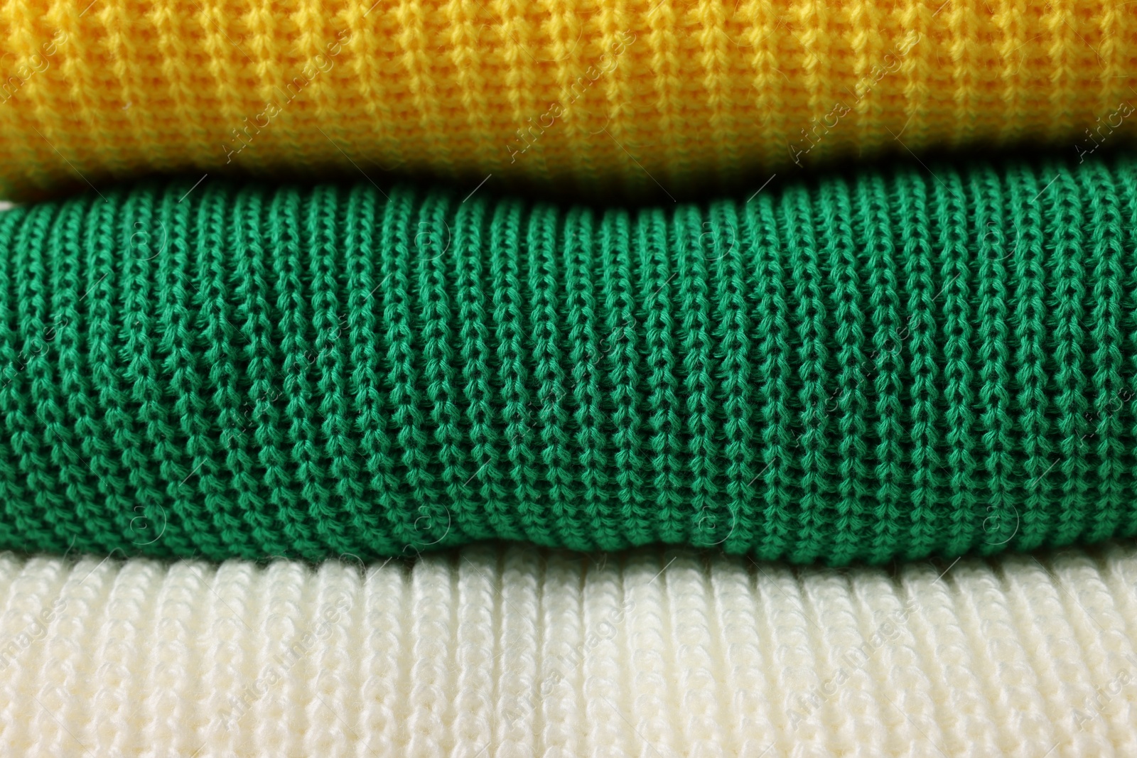 Photo of Stack of casual warm sweaters as background, closeup view