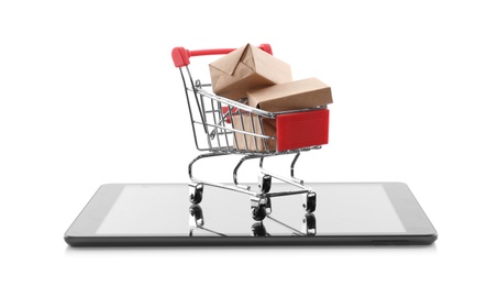 Internet shopping. Small cart with boxes and modern tablet on white background