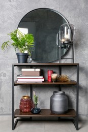 Photo of Stylish round mirror, lamp and houseplant on stand indoors. Interior design