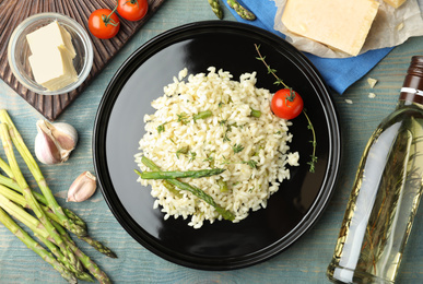 Photo of Delicious risotto with asparagus served on blue wooden table, flat lay