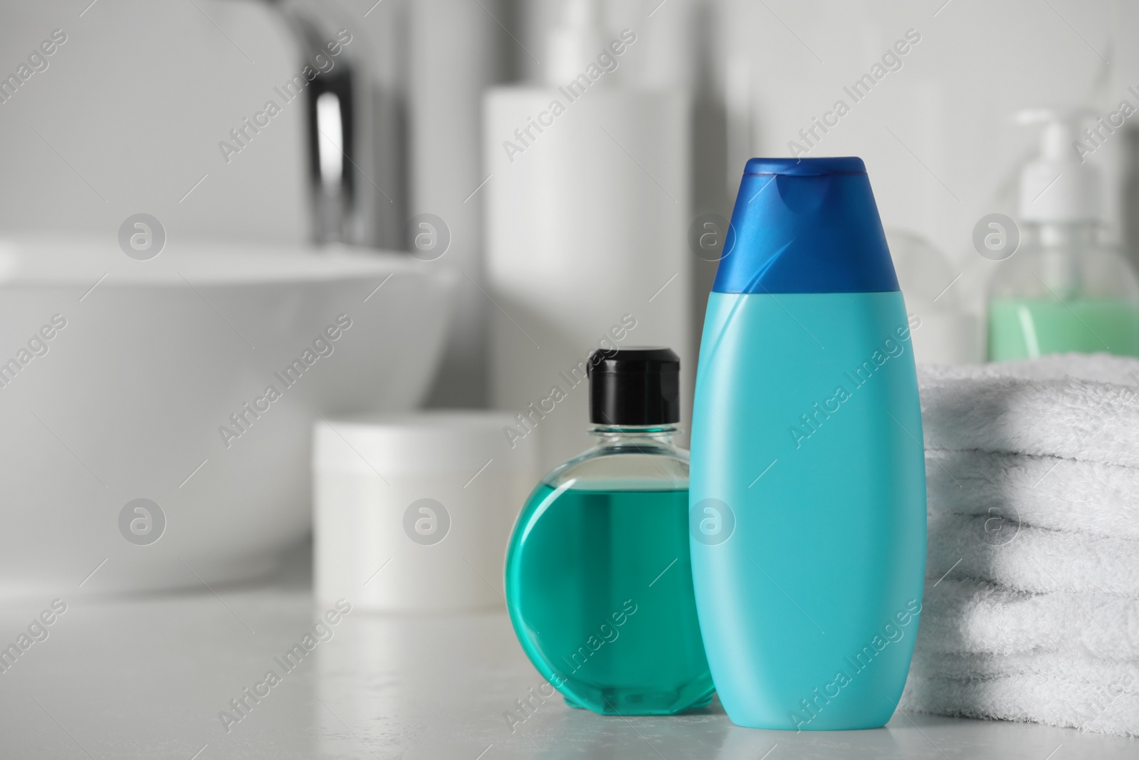 Photo of Shampoo, shower gel and stacked towels near sink on bathroom counter, space for text