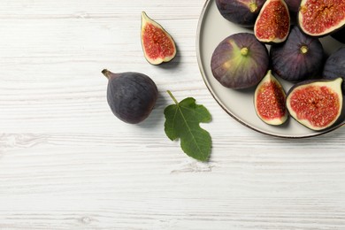 Whole and cut ripe figs with leaf on white wooden table, flat lay. Space for text