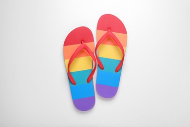 Photo of Rainbow flip flops on white background, top view. LGBT pride