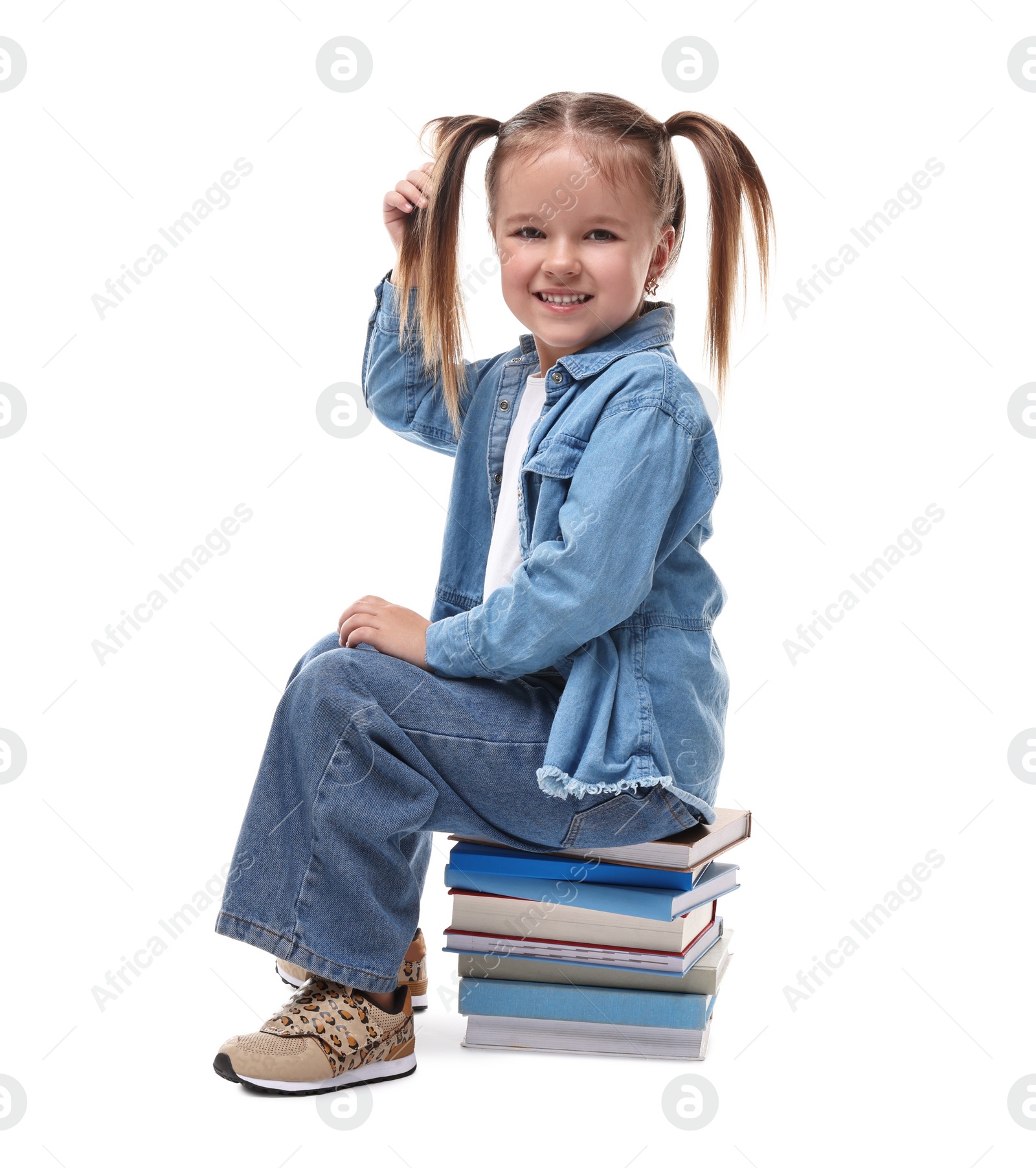 Photo of Cute little girl sitting on stack of books against white background